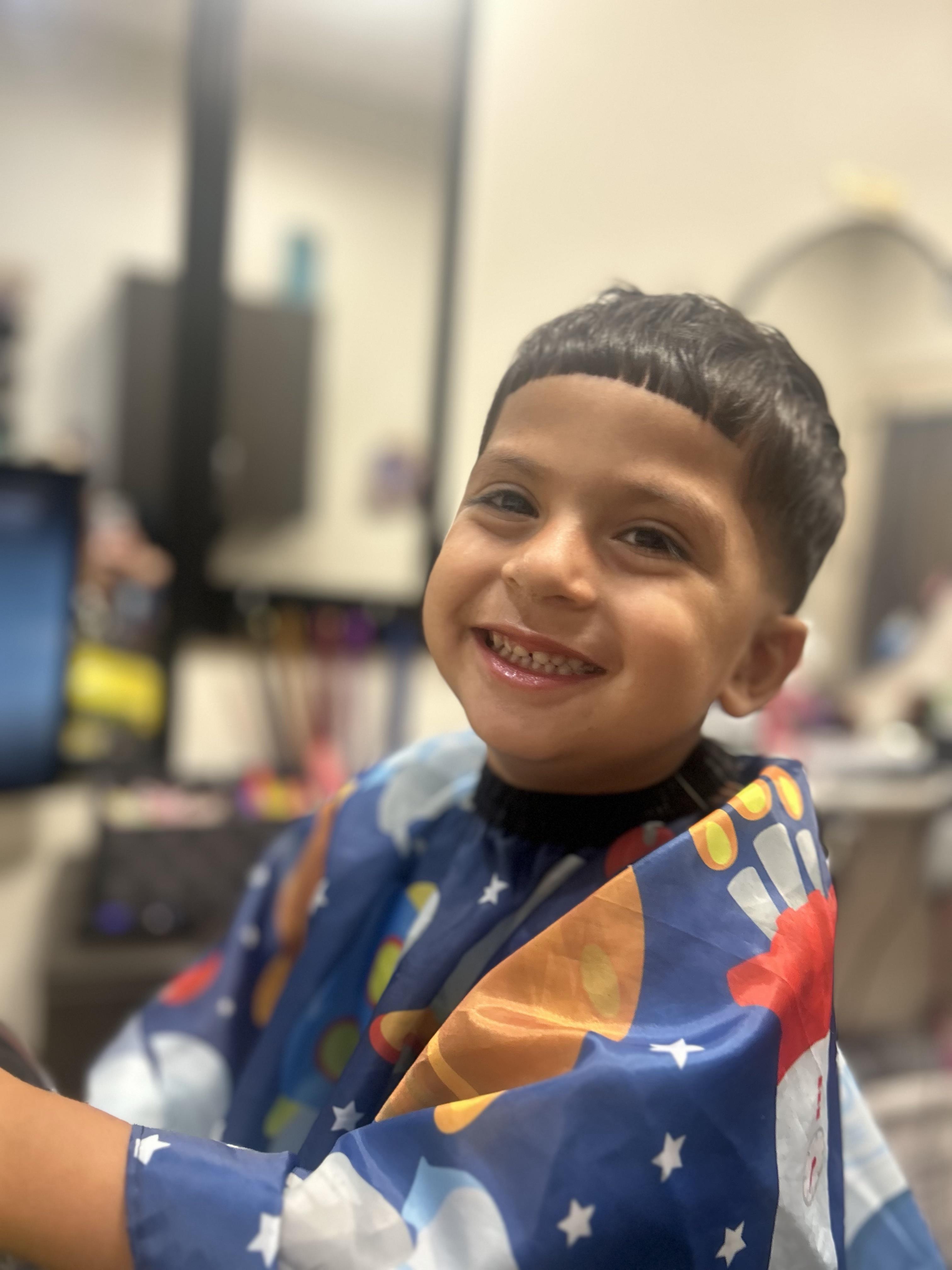 Happy child getting a haircut at Timeless Cuts